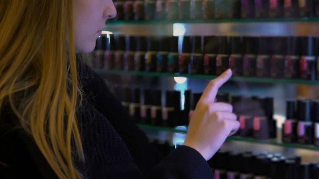 Female buyer looking at beauty shop window choosing nail polish present, shellac