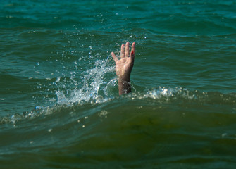 A girl drowning in the sea. Hand over water asking for help.