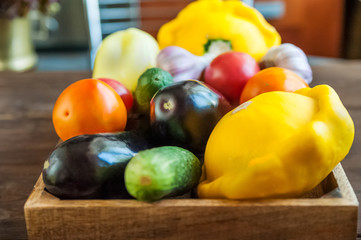 Beautiful picture of vegetables. Focus on young squash patsons. Patissons, eggplants, cucumbers, tomatoes, peppers, garlic in a wooden box. Texture of vegetables is natural. Background and space for t