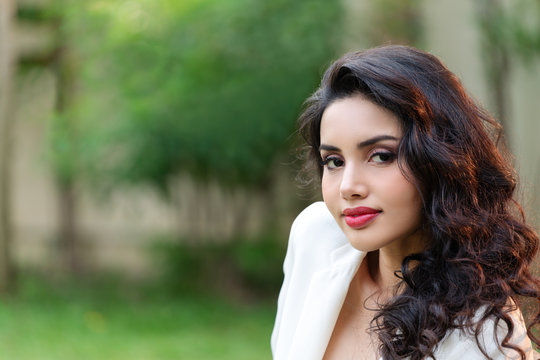 Side view portrait of attractive young asian brunette woman looking at camera smiling with confident lifestyle concept. Gorgeous look of young indian businesswoman with perfect makeup and copy space.