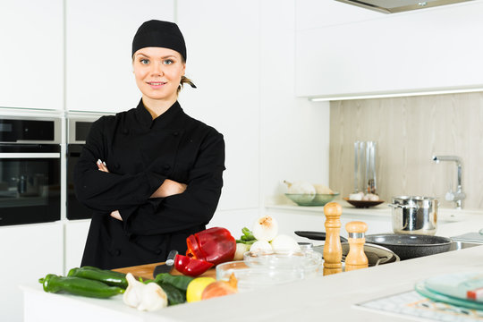 Professional woman chef  in black uniform standing on kitchen