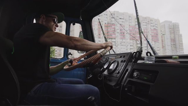 The driver of the garbage truck ZIL spins the steering wheel in a standing car.