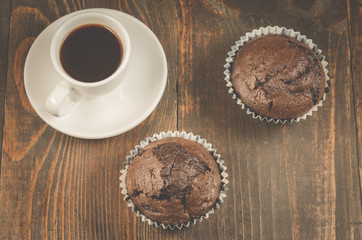 coffee cup and a two chocolate muffin/coffee cup and a two chocolate muffin on a wooden background, top view