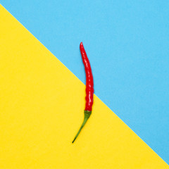 Red chili pepper on blue and yellow background