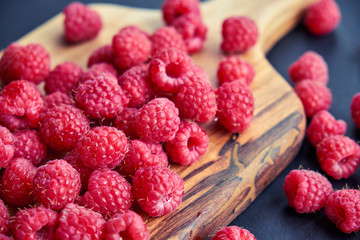 Fresh organic raspberries on black background. berries on a wooden spoon