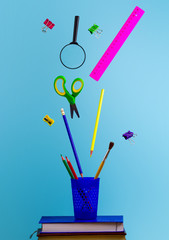 Flying school supplies on a blue background. School concept.
