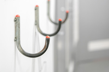 A series of Hooks for bags is attached to the wall of a supermarket.