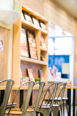 many seat steel chair and wooden table in fast food.beautiful interior at fast food.many seat for custumer sit and eating in fast food shop.custumer standing order food to cashier background.