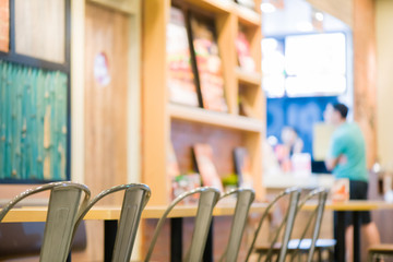 many seat steel chair and wooden table in fast food.beautiful interior at fast food.many seat for custumer sit and eating in fast food shop.custumer standing order food to cashier background.