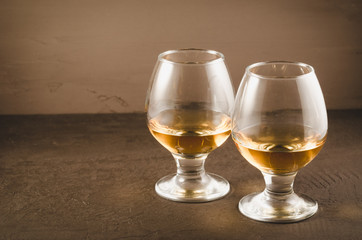 two glasses with cognac/two glasses with cognac on a dark stone background, selective focus
