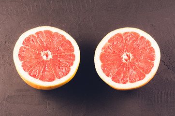 two halves of grapefruit/two halves of grapefruit on a dark stone background, top view