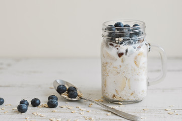 Overnight oats with whole grain cereal, fresh bluberries and coconut milk served with a spoon on wooden table. Healthy dessert for breakfast - 215968315