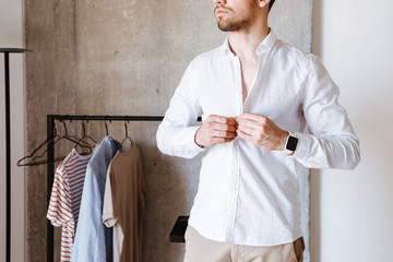 Cropped image of a man in white shirt buttoning up