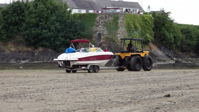 A tractor pulls a boat out of the sea