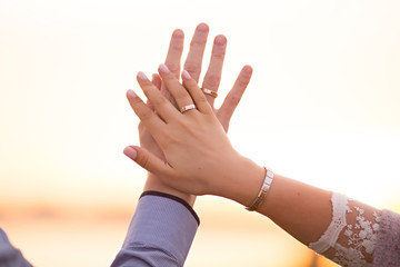 two wedding rings on hand at sunset background
