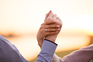 Fototapeta na wymiar two wedding rings on hand at sunset background