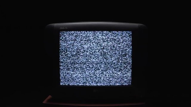 TV screen on at night with a white noise. Stock. Static noise on the old TV screen in the dark