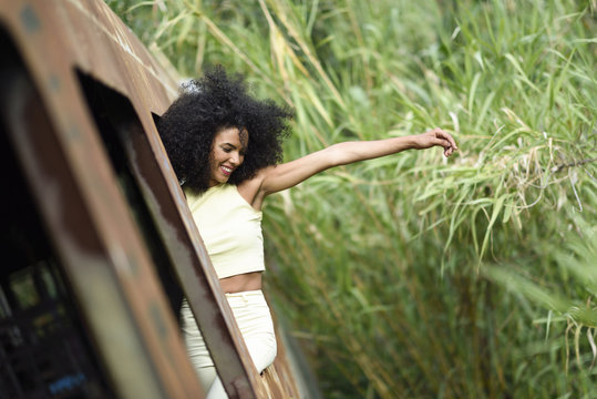 Fashionable young woman leaning out of abandoned and destroyed old train