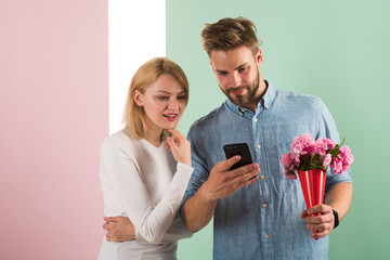 Guy with phone and bouquet of flowers, pastel pink and green background. Romantic concept. Man...