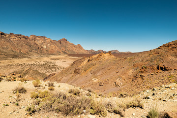 Fototapeta na wymiar View of landscape of Teide National Park on Tenerife, Canarias islands, Spain. Yellow and black sand and distance view of mountains roads and volcano.