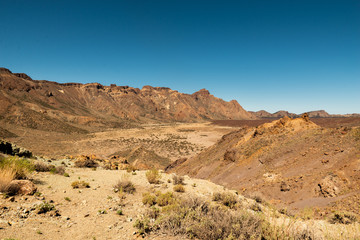 Fototapeta na wymiar View of landscape of Teide National Park on Tenerife, Canarias islands, Spain. Yellow and black sand and distance view of mountains roads and volcano.