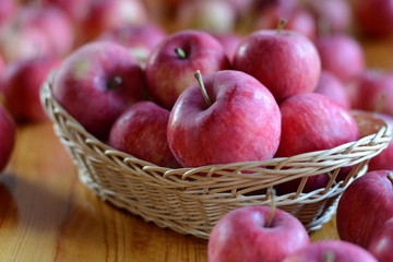 Apples in basket on wooden background. Harvest time, autumn, many red apples.