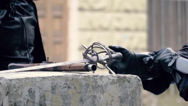 Sword and musket, in the background musketeer puts on gloves