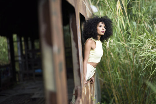 Portrait of fashionable young woman leaning out of abandoned and destroyed old train