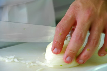 Hand with knife cutting onion