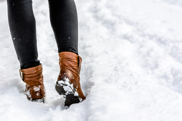 Woman walking in snow boots, winter womens shoes on the feet and legs dressed in leggings