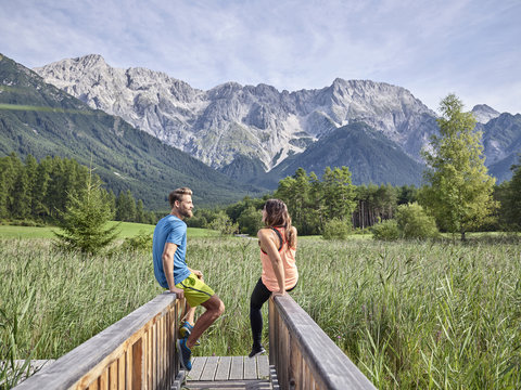 Austria, Tyrol, Mieming, couple resting on a boardwalk in the mountains