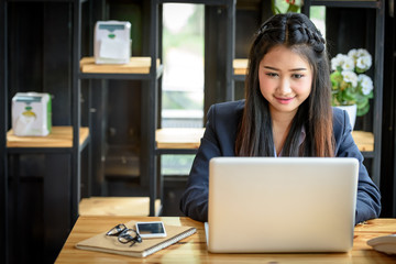 Beautiful Asian businesswoman is using a laptop computer in her office. Business and Technology Concepts.