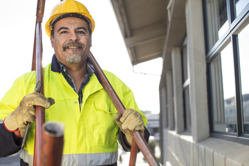 Portrait of construction worker holding pipes
