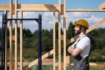 The man is a builder on the roof of a wooden frame house.