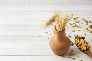 Dry Breakfast of oat flakes, granules and nuts. Muesli on a light table and dry ears in a clay vase...