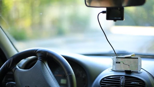 A man gets into the car and turns on the navigator on the smartphone