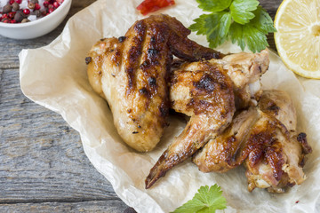 Chicken wings baked on grill with fresh herbs, lemon on wooden background.