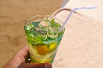 Cold mojito drink on the beach sand and sunbed. Summer vacation concept image.