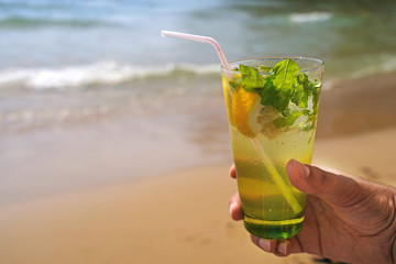 Cold mojito drink on the beach sand. Summer vacation concept image.