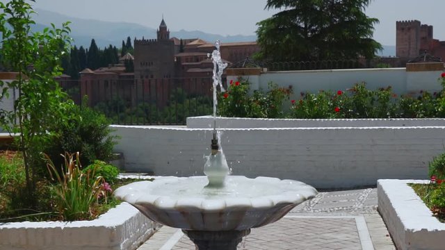 A view of a fountain with the Alhambra behind.