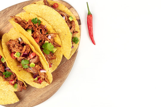 Overhead closeup photo of Mexican tacos with pulled meat, avocado, chili peppers, cilantro, with copy space, on white