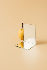 yellow pear and two mirrors on beige table