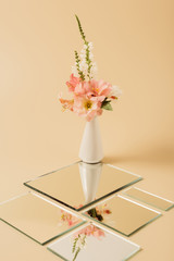 lily flowers in vase reflecting in mirrors on beige table