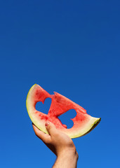 Male holding slice of watermelon heart cut towards the sky. Copy space.