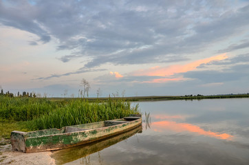 Fototapeta na wymiar Breathtaking summer scenery with old wooden boat in warm evening sunlight.