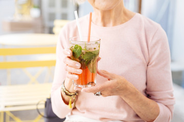 Option when hot. Close up of senior female hands rising cold drink
