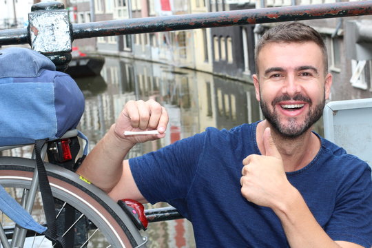 Man giving thumbs-up holding joint in Amsterdam 