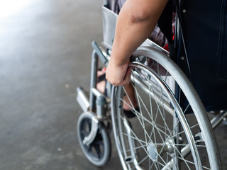 A disabled man is sitting in a wheelchair. He holds his hands on the wheel. Handicap people Concept.