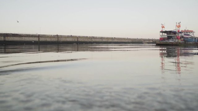 4k Footage of slow water moving towards the bay with a boat in the background.Taken at Ramsgate port in the UK