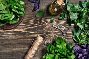 Variety of fresh organic herbs on wooden background. Freshly harvested herbs including basil, arugula. Top view. Copy space.